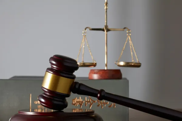 An image of a justice scale and a wooden gavel on a table.