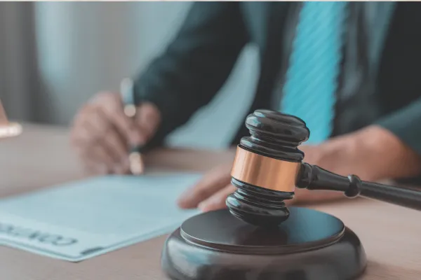 An image of a lawyer writing at his desk beside a wooden gavel.